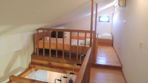 A loft bedroom with a wooden staircase, a small window, and a bunk bed.