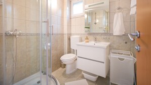 A bathroom with a glass-enclosed shower, a toilet, a sink, and a mirror.