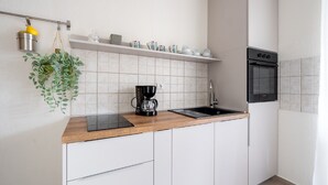 A modern kitchen with white cabinets, a wooden countertop, a coffee maker, a sink, and a microwave.