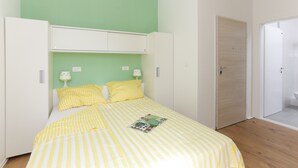 Una camera da letto con un letto, due comodini, un armadio e una porta che conduce al bagno.