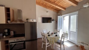 Une cuisine équipée d’un four encastré, d’un réfrigérateur et d’un coin repas avec une table et des chaises.