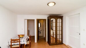 Zona de menjador amb taula per a dos, un armari de fusta i una porta que dona a una altra estança.