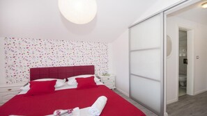 Une chambre moderne avec une couvre-lit rouge, des oreillers blancs et un papier peint à motifs floraux.