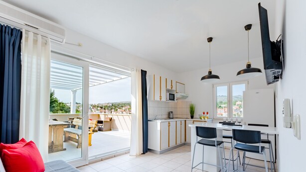 Une cuisine moderne avec un coin repas, de grandes fenêtres et une vue sur l’extérieur.
