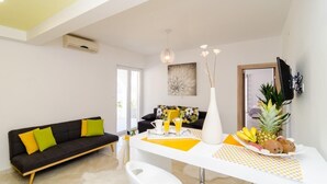 Een moderne woonkamer met een zwarte bank, een witte salontafel en een eethoek met een witte tafel en een gele placemat.