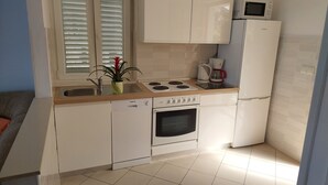 A compact kitchen with white cabinets, a built-in oven, a microwave, and a coffee maker. - Apartments Matea - Two-Bedroom Apartment with Sea View and Balcony (Stikovica)