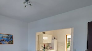 A living room with a sofa, a coffee table with a magazine, and a kitchen area visible through an open doorway. - Apartments Matea - Two-Bedroom Apartment with Sea View and Balcony (Stikovica)