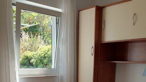 A bedroom with a bed, a window with curtains, a wardrobe, and a ceiling fan. - Apartments Matea - Two-Bedroom Apartment with Sea View and Balcony (Stikovica)