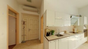 A modern kitchen with white cabinets, a stainless steel sink, and a built-in oven.