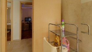A bathroom with a shower, a toilet, and a shelf with toiletries.