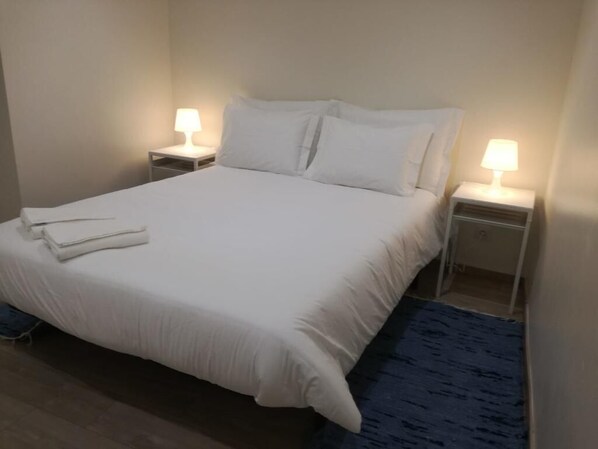 Relax in a cozy space with a neatly made bed and two bedside tables, each with a lamp.