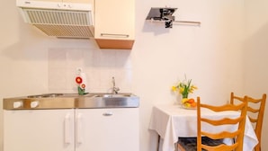 A kitchen with a stove, sink, and a wall-mounted device. - Apartments Villa Ivka - Studio Apartment (Dubrovnik)