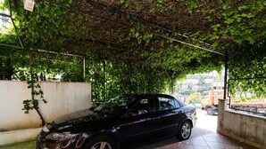 A black car parked under a covered area with a tiled floor and a concrete wall. - Apartment Berk - One-Bedroom Apartment with Terrace (Dubrovnik)