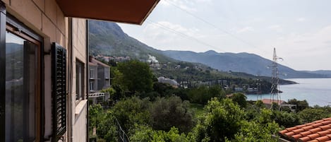 Uma varanda com vista para uma cidade costeira, montanhas e uma torre de transmissão.