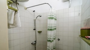 A small, tiled bathroom with a shower, a toilet, and a green shelf. - Rooms Pile - Double Room with Patio (Dubrovnik)