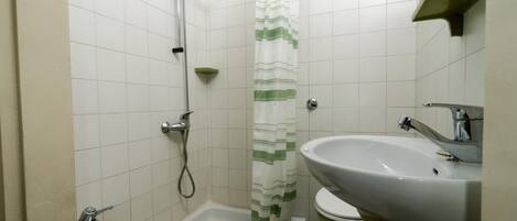 Une salle de bain avec une douche, deux lavabos et des toilettes.