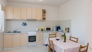 A compact kitchen with beige cabinets, a microwave, an oven, and a dining table with chairs.
