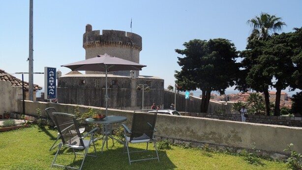 A courtyard with a round tower, outdoor seating, and a sign reading "APARTMENT". - Apartments Kapelica - Studio apartment (Dubrovnik)