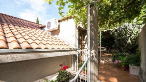 Un cortile con tetto in tegole, piante in vaso e una scala che porta a una porta.