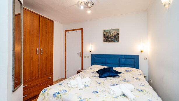 Een slaapkamer met een bed, een kledingkast en twee wandlampen.