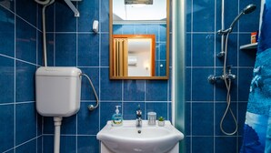 Een badkamer met een wit wastafel, spiegel, douche en toilet.
