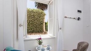 Quarto com janela, uma pequena mesa com planta em vaso e uma cadeira.