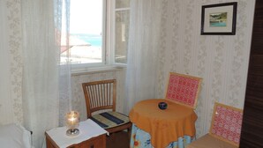 Una stanza con un letto, una sedia, un tavolino con una lampada e una finestra vista spiaggia.