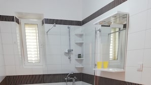 Une salle de bain équipée d’une douche, de toilettes, d’un lavabo et d’un miroir.