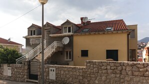 A two-story building with a stone wall, a metal gate, and a staircase leading to the upper floor. - K-Apartments - Double or Twin Room with Garden View - A3 (Dubrovnik)