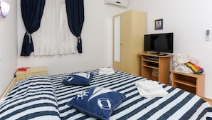 A bedroom with a bed, a TV, a wardrobe, and a window with curtains. - K-Apartments - Double or Twin Room with Garden View - A3 (Dubrovnik)