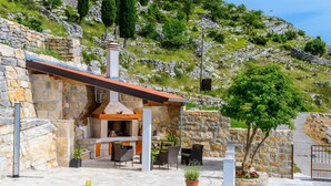 Un edificio de piedra con piscina, mobiliario exterior y vistas a una colina.