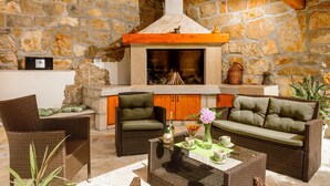 Una habitación de paredes de piedra con chimenea, muebles de mimbre y una mesa de centro.