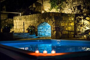 Une piscine avec des murs en pierre et une arche en pierre.