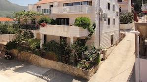 A two-story building with a balcony, a stone wall, and potted plants. - Apartments Magda- Standard Backside Studio Apartment (Cavtat)