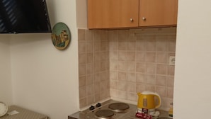 A small kitchen with a gas stove, a coffee maker, and a wall clock. - Apartments Magda- Standard Backside Studio Apartment (Cavtat)
