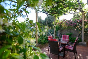 Une terrasse extérieure avec des meubles en osier et une pergola.