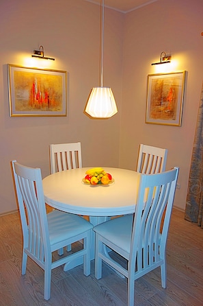 A dining area with a round table, four white chairs, and two wall-mounted light fixtures.