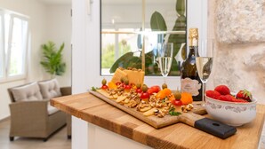 Une table en bois sur laquelle on a disposé un plateau de fromages, des raisins et une bouteille de vin.
