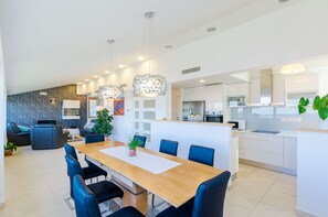 A modern kitchen with white cabinets, a stainless steel range hood, and a large island.