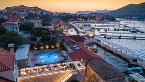 A waterfront hotel with a swimming pool, outdoor seating, and a view of the harbor. - Orka Apartments - Comfort Apartment (2 Adults + 1 Child) (Dubrovnik)