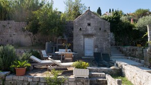 A stone building with a door, surrounded by greenery and a stone wall. - Orka Apartments - Comfort Apartment (2 Adults + 1 Child) (Dubrovnik)
