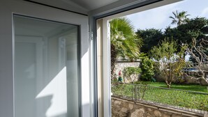 Blick von einem Balkon mit Steinmauer, einer Palme und einem Garten mit verschiedenen Pflanzen.
