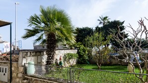 Eine Steinmauer mit einer Palme, einem Metallzaun und einer Statue.