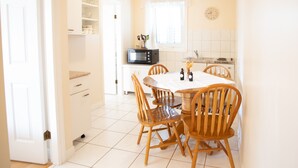 Una cocina luminosa con armarios blancos, un microondas y una mesa de comedor con sillas de madera.