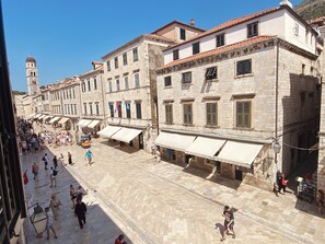Una strada storica con edifici in pietra, un'imponente torre e una vivace zona pedonale.