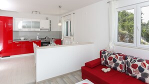 Una cocina moderna con armarios rojos y blancos, una isla central y un sofá rojo con cojines estampados.