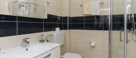 A modern bathroom with a glass shower enclosure, a white sink, and a toilet.