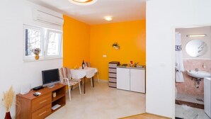 Un espacio habitable compacto con comedor, kitchenette y baño.