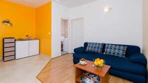 Un espacio habitable compacto con kitchenette, un sofá y una mesa de centro.