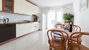 Une cuisine moderne avec des meubles blancs, un lave-vaisselle et un coin repas comprenant une table et des chaises.